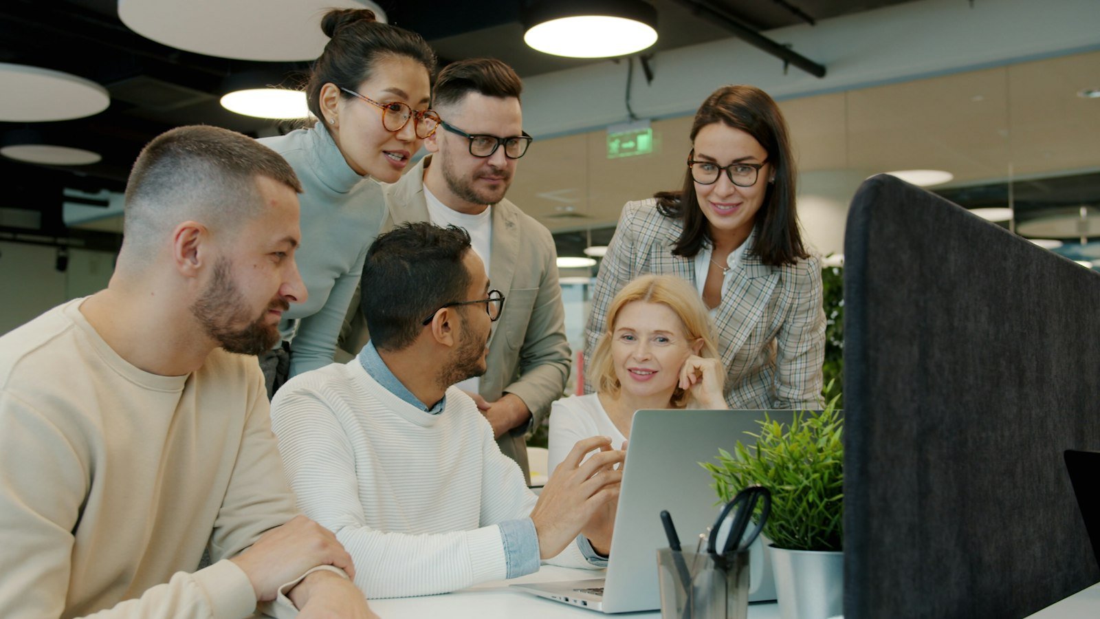 A diverse team collaborating around a laptop in a modern office
